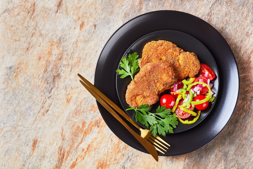 A chef frying chicken cutlets in a skillet, showing golden-brown cutlets being turned with tongs, illustrating best frying practices.