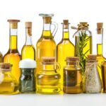 Glass bottles of olive, avocado, and canola oil in a modern kitchen setting, highlighting the diversity of cooking oils.